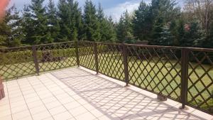 une clôture métallique sur une terrasse avec un champ dans l'établissement WILIMY Dom nad jeziorem Dadaj, à Wilimy