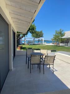 a patio with a table and chairs and the beach at Zinozis Beach Apartments in Vourvourou