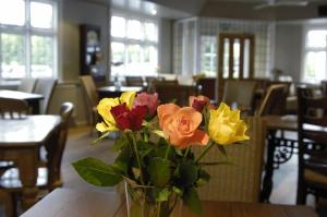 a vase of flowers on a table in a restaurant at The White Lion Inn in Hampton in Arden