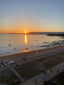 um pôr-do-sol numa praia com o pôr-do-sol em Playa Compostela em Vilagarcía de Arousa