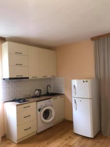 a kitchen with a white refrigerator and a washing machine at guesthouse MUKHA in Oni