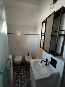 La salle de bains blanche est pourvue d'un lavabo et de toilettes. dans l'établissement CasAda, à Spongano