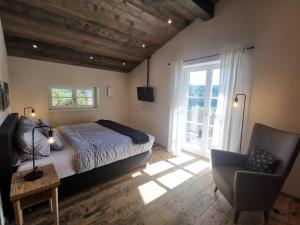 a bedroom with a bed and a chair and a window at Kräuterhof Chalets in Missen-Wilhams