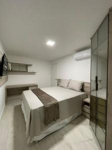 a bedroom with a large bed and a glass wall at Apartamento na Praia dos Anjos in Arraial do Cabo