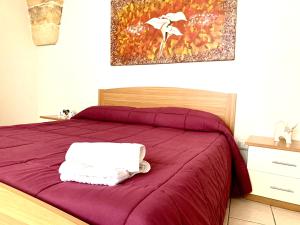 a bedroom with a bed with purple sheets and a painting at LA PICCOLA DIMORA in Carovigno