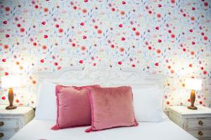 1 dormitorio con 1 cama blanca con flores rojas en la pared en B&B Calamoresca, en Àrbatax