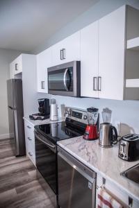 a kitchen with white cabinets and a black stove top oven at AIR & ROAD TRAVELERS' PERFECT SPOT! + FULL KITCHEN in Regina
