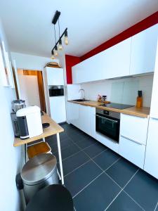 a kitchen with white cabinets and a black floor at Charme et Douceur By UTA HOUSE in Saint-Denis