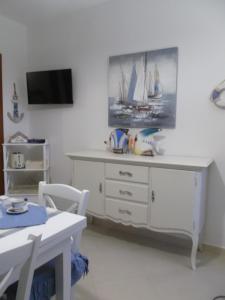 uma cómoda branca num quarto branco com uma mesa em L'Ancora suite em Orosei