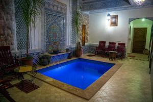 a swimming pool in a room with chairs and a table at Riad Nouhal in Marrakesh