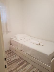 a white bed in a room with a white wall at Braavos Apartment 2 - Šibenik city center in Šibenik
