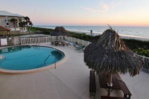 una piscina con sombrilla de paja y la playa en Chateau 8W, en Clearwater Beach