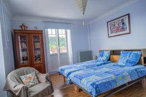 een blauwe slaapkamer met een bed en een stoel bij Gîte Le Noisetier in Munster