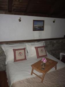 Una cama con sábanas blancas y una mesa con flores. en Stone house Castellum, en Kaštela