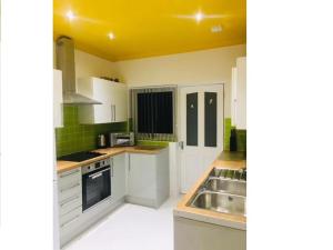 a kitchen with white cabinets and a sink at Townhouse @ Westminster Street Crewe in Crewe