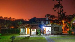 uma casa à noite com um céu vermelho em Recanto Meu Pedacinho de Chão em Visconde de Mauá