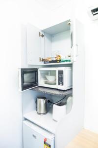 a kitchen with white cabinets and a microwave at Sutherland Motel in Sutherland