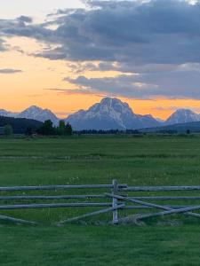 a fence in a field with mountains in the background at Teton Cabins in Moran