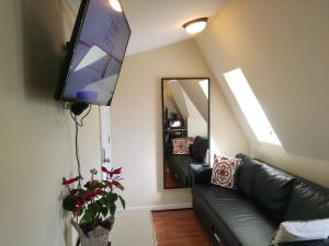 a living room with a black leather couch and a mirror at Most Economical Room in Center Washington DC in Washington, D.C.