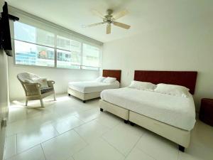 a bedroom with two beds and a chair and a window at Hermoso apartamento familiar /acceso directo a la playa. Morros 3 in Cartagena de Indias