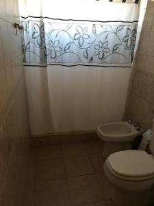 a bathroom with a toilet and a shower curtain at La Ponderosa in Caleta Olivia