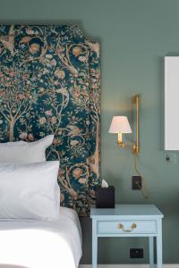 a bedroom with a bed and a wall with a floral wallpaper at The Observatory Hotel Christchurch in Christchurch