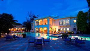 a large building with tables and chairs next to a pool at Samode Haveli in Jaipur