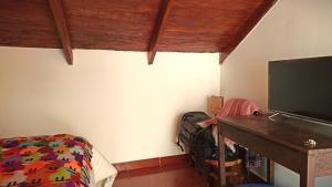 a bedroom with a bed and a desk and a television at Los Apus Ollantaytambo in Cusco