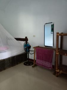 Schlafzimmer mit einem Bett und einem Spiegel auf einem Tisch in der Unterkunft Brown Bamboo Bukit Lawang in Bukit Lawang