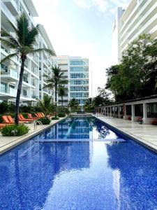 une grande piscine bleue au milieu d'un bâtiment dans l'établissement Hermoso apartamento familiar /acceso directo a la playa. Morros 3, à Carthagène des Indes