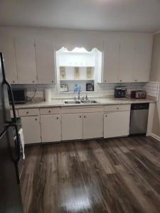 a kitchen with white cabinets and a wooden floor at 3 Bedroom Cozy Home Minutes From Tims Ford Lake in Winchester
