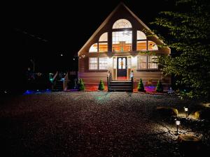 a house is lit up at night with lights at Nature Escape Resort With Large Private Deck, Hot Tub, BBQ Grills, at Arrowhead Lake with 3 Pools, 4 Beaches at the Lakes and MORE in Thornhurst