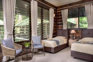 una camera con due letti, sedie e finestre di Rompin Rainforest Lodge a Kuala Rompin