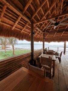 a restaurant with tables and chairs and a straw roof at Sumba Beach House in Waikabubak