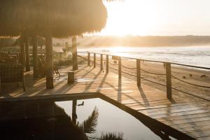 a boardwalk on the beach with the sun setting at Sumba Beach House in Waikabubak