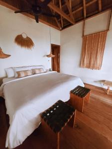 a bedroom with a large white bed and two chairs at Sumba Beach House in Waikabubak