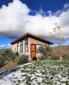 a small house with an orange door on a hill at ArribadelValle - Casas de Altura in Potrerillos