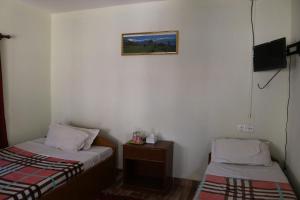a small room with two beds and a tv at Gurkha Lodge in Pokhara