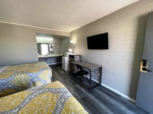 Habitación de hotel con 2 camas y escritorio con TV. en Belle Aire Motel en Globe
