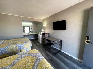 a hotel room with two beds and a desk with a television at Belle Aire Motel in Globe