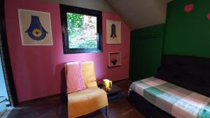 a room with two beds and a window and a chair at Pitaya Suítes in Cunha +82 photos