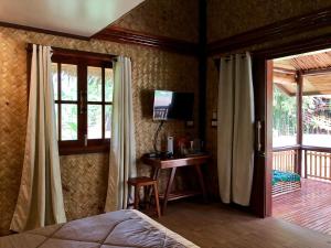 a bedroom with a bed and a desk with a television at Babaland in New Agutaya