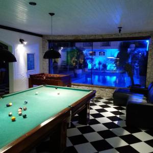 a billiard room with a pool table and a swimming pool at Perohouse in Cabo Frio