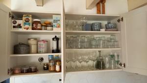 a kitchen cabinet filled with glasses and bottles at Het Zeepaartje, knus en gezellig in Noordwijkerhout