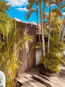 a wooden fence with palm trees on a wooden deck at LES CERISIERS BEACH RESIDENCE-Luxury 3Bd, Pool, Big Terrasse, 50mts from beach in Flic-en-Flac