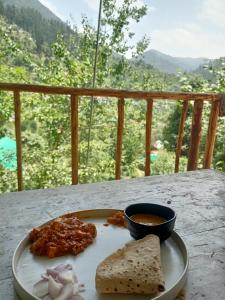 Jibhi的住宿－LITTLE WOOD TREEHOUSE，盘子,带面包和一碗酱