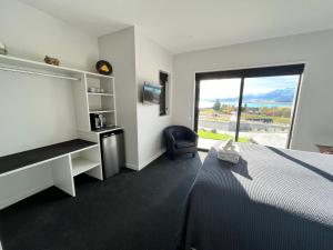 um quarto de hotel com uma cama, uma secretária e uma janela em Starry Vista-Beta em Lake Tekapo