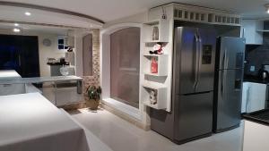 a kitchen with a stainless steel refrigerator and shelves at Perohouse in Cabo Frio