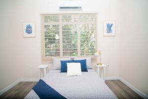Un dormitorio con una cama con almohadas azules y una ventana en RayneBow Chateau - Chic City Getaway en Puerto España