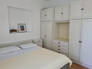 ein weißes Schlafzimmer mit weißen Schränken und einem Bett in der Unterkunft Apartments Stosa - with parking in Nin
